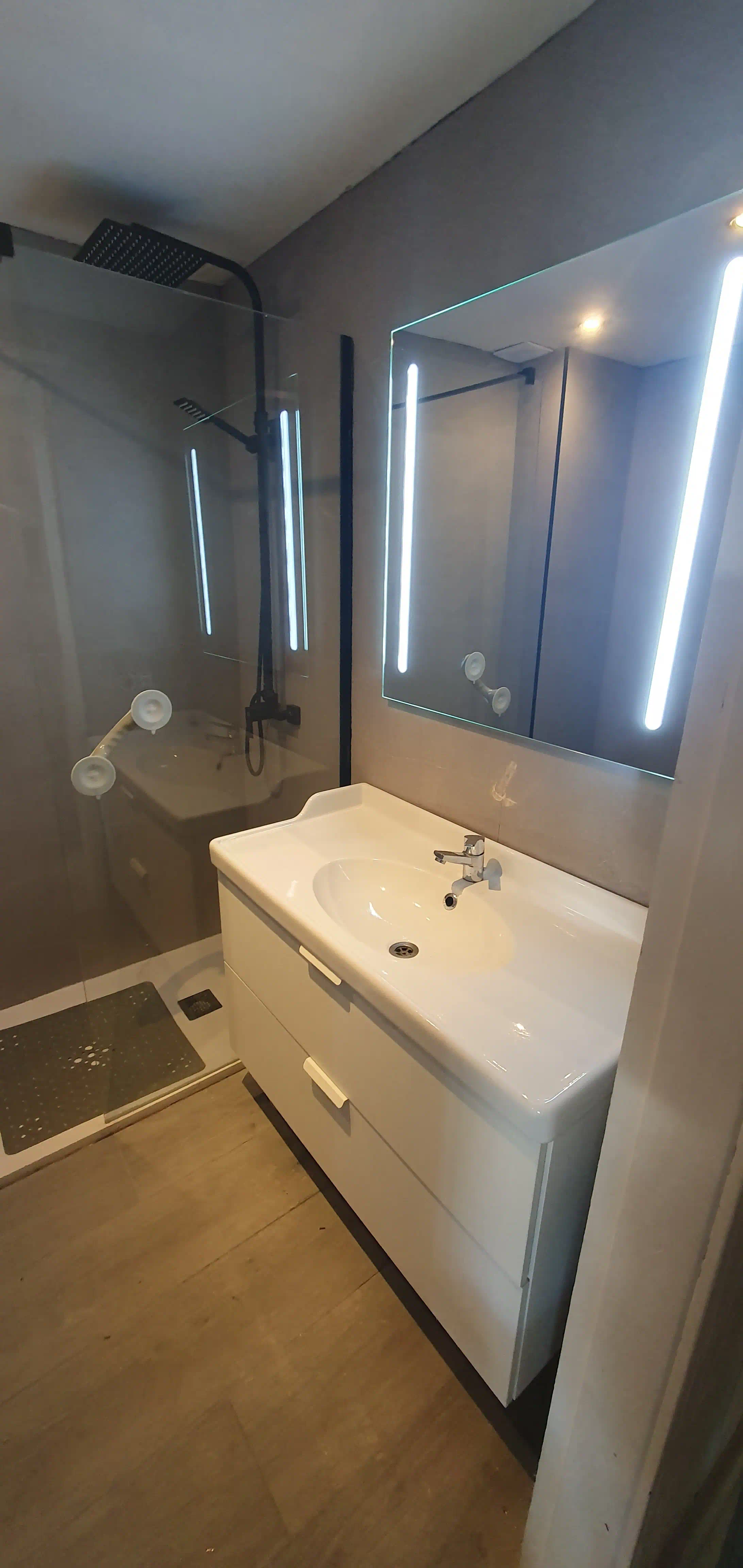 Baño principal finalizado con porcelanato español gris cemento 60x60 y suelo efecto madera