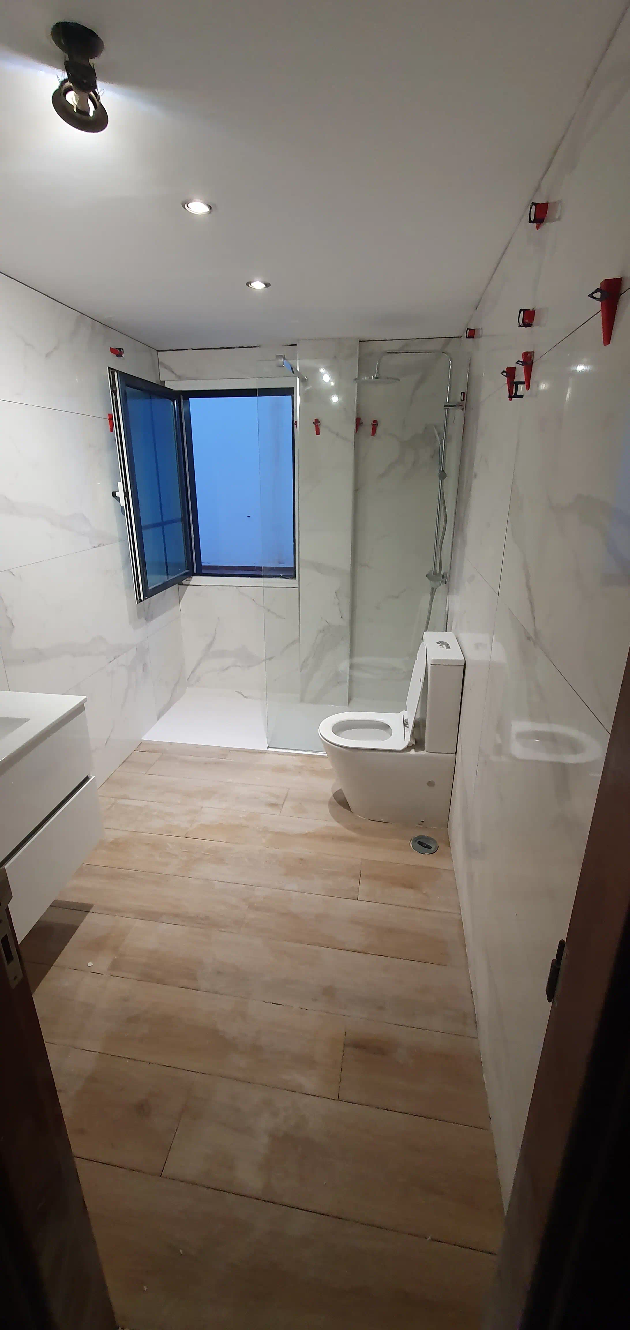 Baño renovado en La Trigaleña con porcelanato rectificado 60x120 efecto mármol y suelo efecto madera