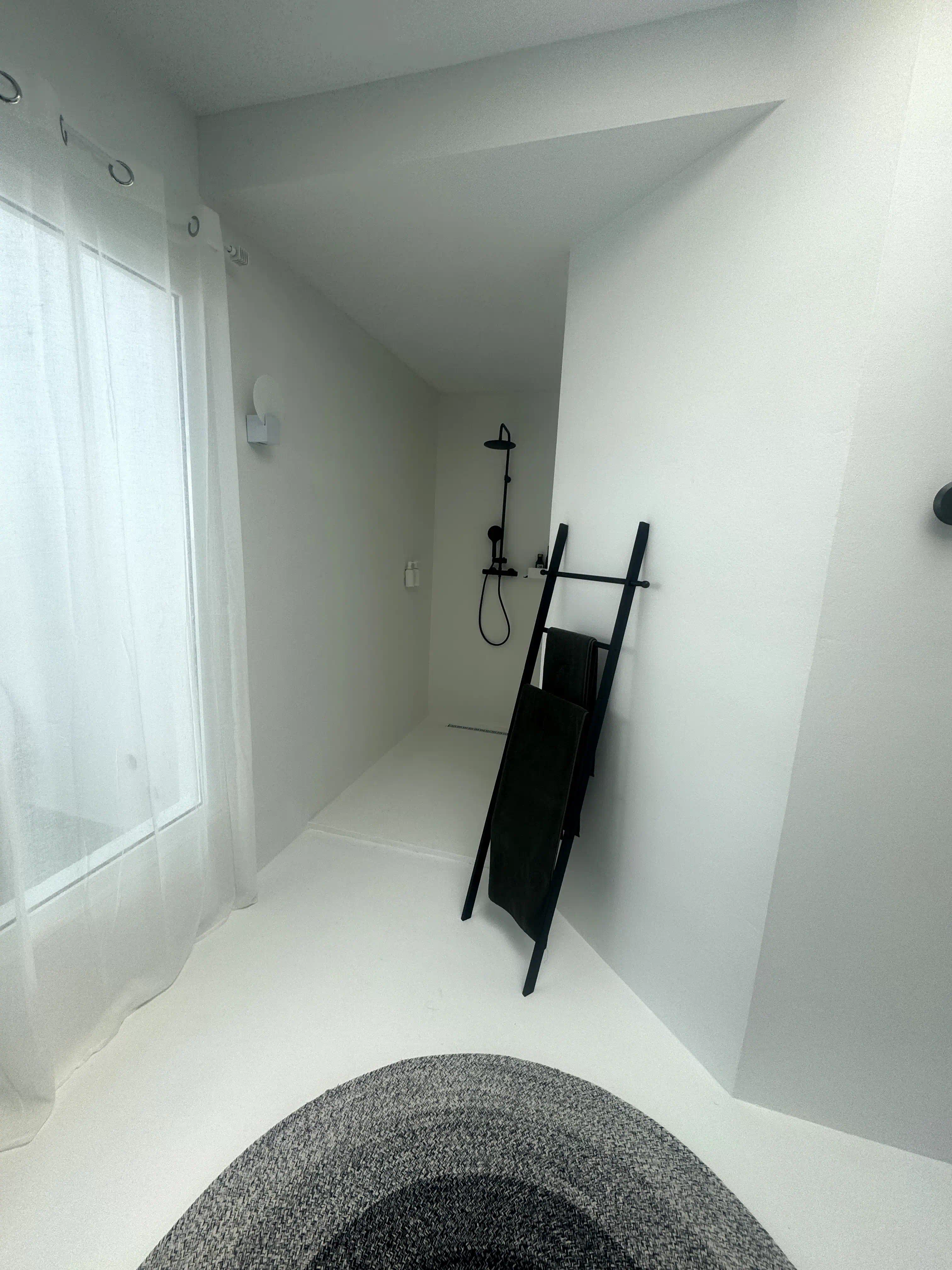 Zona 1 del baño en quinta de Guataparo con encimera flotante de hormigón, microcemento blanco y piedra volcánica